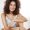 Portrait of young beautiful african girl in sleepwear smiling looking at camera sitting resting in chair at home.
